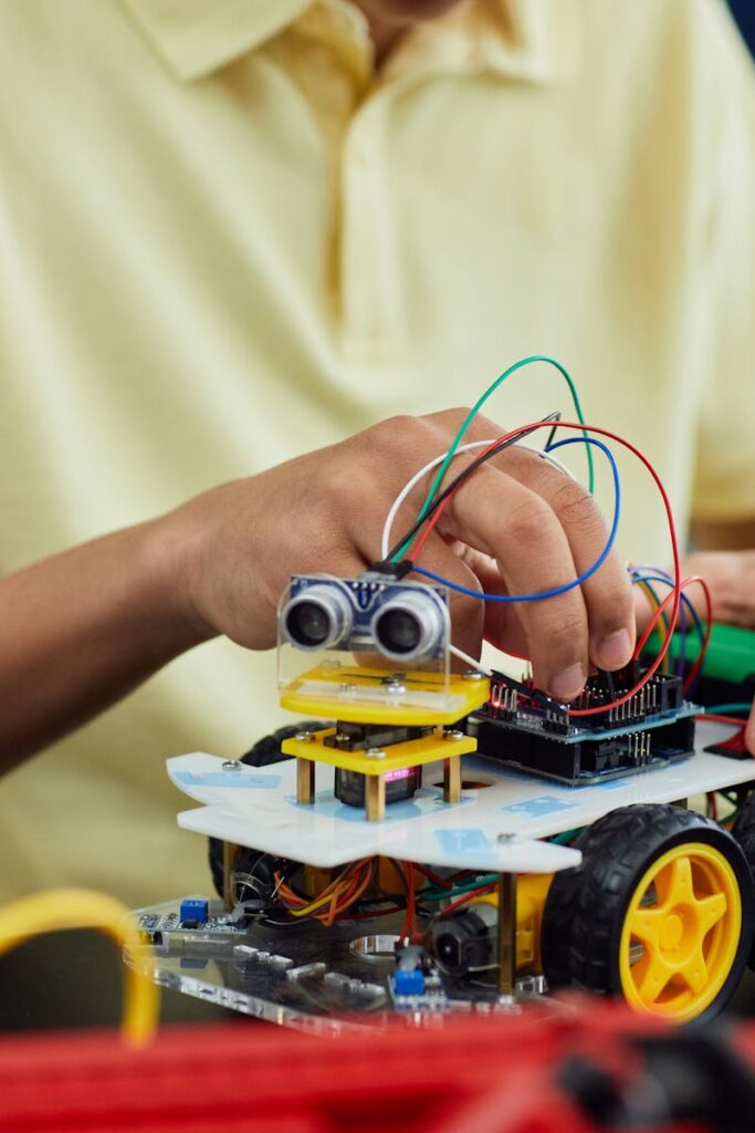 A child engaging in a STEM activity by assembling a robotic toy car featuring electronics and wiring.